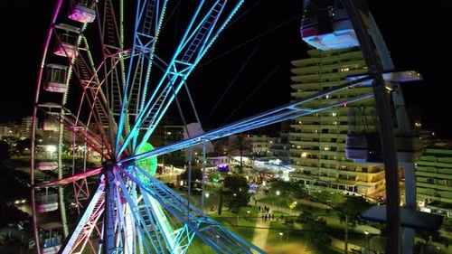 Illuminated Ferris Wheel Spinning at Night in City