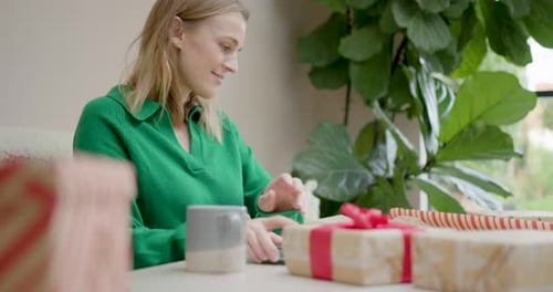 Female Buying Christmas Presents using Phone at Home and Wrapping Gifts