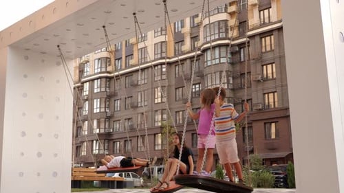 Happy Children are Riding Standing on a Swing in the Yard