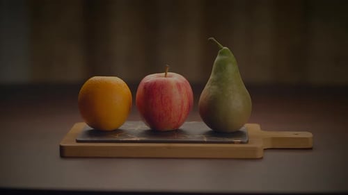 Three Fruits are Arranged on a Wooden Cutting Board