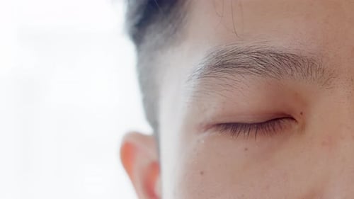 Close up of Asian Man's face. Attractive boy with beautiful eyes. Caucasian young male model with ey