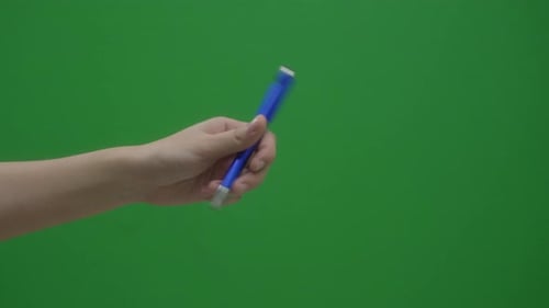 Human Hand With A Blue Pen In Green Screen Background. Close Up