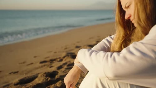 Young Woman Sits on Beach with Candies
