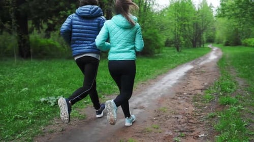 Sportive young people running. Couple run in the park during rainy day