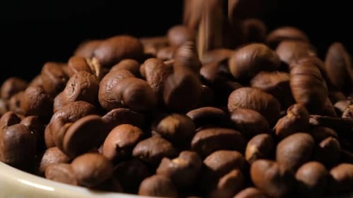 Slow motion of roasted coffee beans falling.