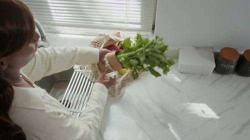Woman Unpacking Grocery Bag with Fresh Fruits and Vegetables