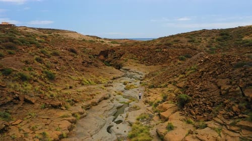 Aerial View of a Female Hiker Walking at Seashore Next to Volcanic Rocks with Whimsical Shape Due