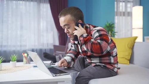 Man Talks on Phone While Using Laptop at Home