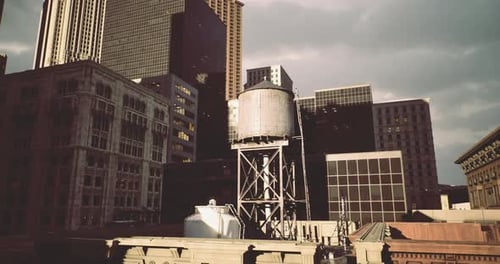 Horizonte urbano con torre de agua y edificios imponentes durante la puesta de sol
