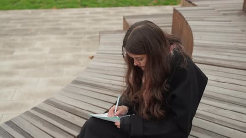 Teen Girl Drawing in Notebook in Public Park