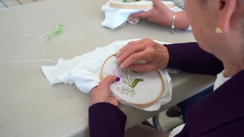 Elder embroidering flowers in art class