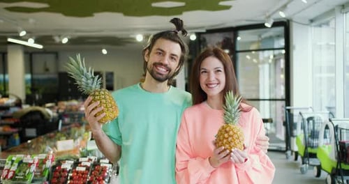 Cheerful Pineapple Presentation Young Brunette Couple Poses and Smiles Holding Pineapples