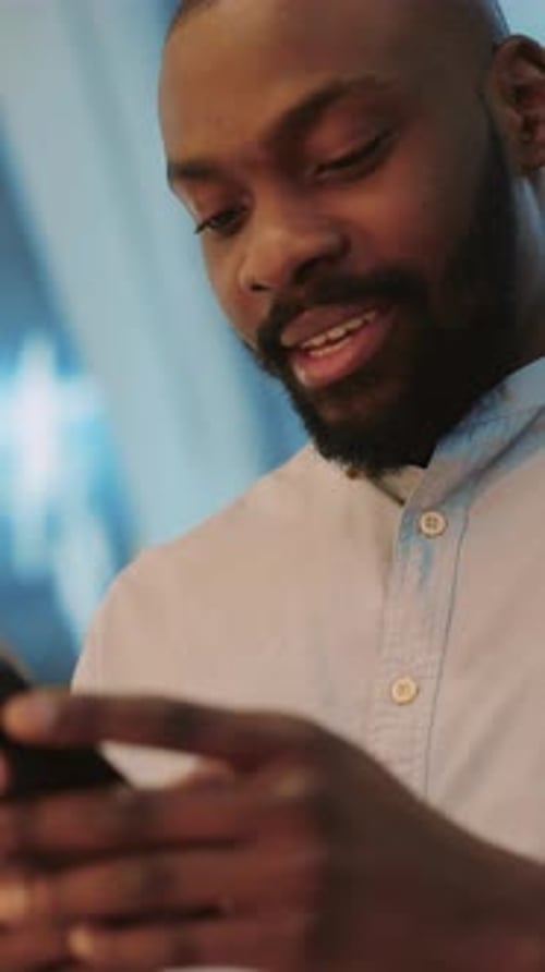 A Man is Deeply Engaged with His Smartphone While in a Modern Urban Setting Around Him