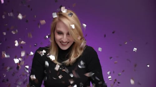 Woman Celebrates as Confetti Falls on Purple Backdrop