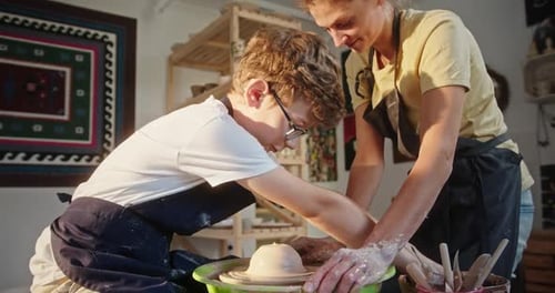 Boy and Woman Shaping Clay on Pottery Wheel