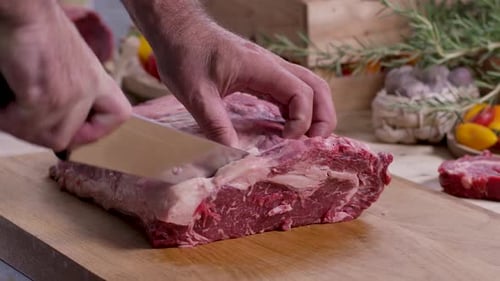 Man cutting raw meat on wooden cutting board