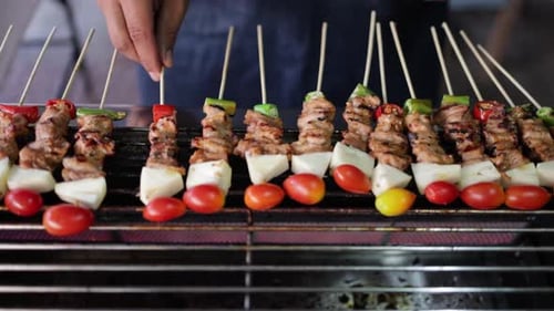 Vendeur de nourriture de rue faisant griller du porc et du poulet au barbecue sur des brochettes ou des brochettes de viande avec des légumes sur f