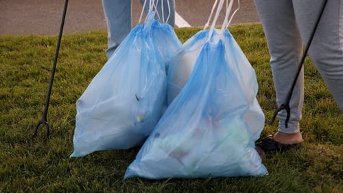 Primer plano de dos voluntarias que salen del parque con bolsas llenas de basura