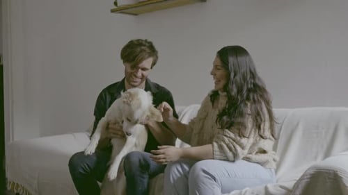 Couple with Dog Sitting on Sofa Indoors