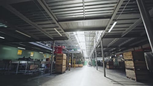 Walking Through a Factory Warehouse with Crates and Pallets for Storage of Supplies