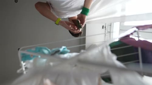 Young Adult Hanging Laundry on Rack Indoors