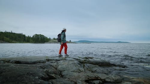 Woman Hiking on Rocky Shoreline Along the Coast
