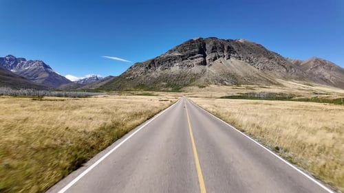 Scenic Highway Journey: Driving Through Mountains and Open Fields on a Sunny Day