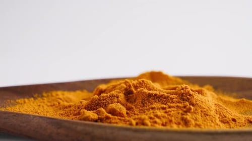 Turmeric Powder Pouring Into Wooden Bowl Aromatic Spice and Cooking Ingredient Concept