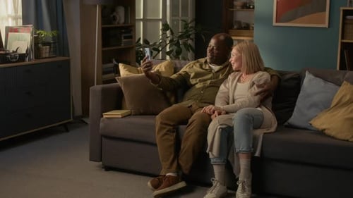 Couple Relaxing on Couch Looking at Smartphone