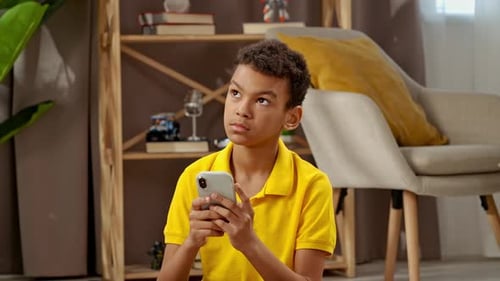 Boy Uses Smartphone Indoors, Smiling and Relaxed