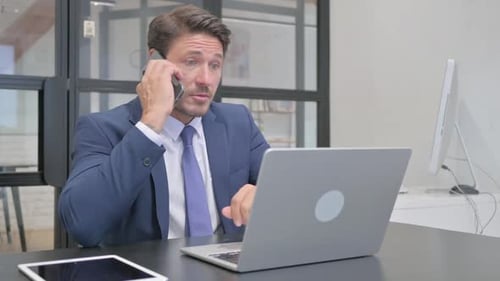 Man in Suit Working in Office on Phone