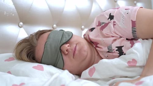 Woman Adjusts Eye Mask Lying in Bed