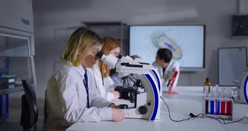 School Students In Biology Lesson Teens Girls Looking To Microscopes Studying Microbiology