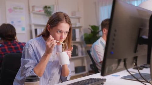 Caucasian businesswoman eatting noodles while work in office at night.