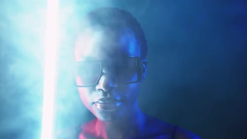 Stylish Woman with Sunglasses Posing near Neon Light
