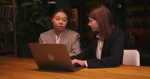 Two Women Work on a Laptop in Office