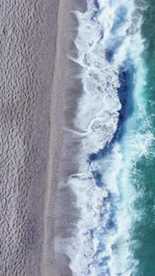 Waves breaking on the beach shore top view
