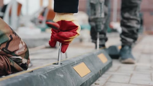 Worker Installing Rubber Parking Wheel Stop on Paved Surface Close Up