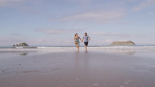 Couple running on sandy beach enjoying tropical honeymoon in costa rica slow motion