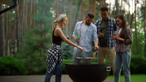 Friends grill meat outdoors at a backyard barbecue