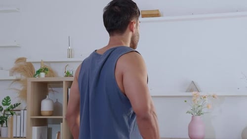 Young asian man lifting dumbbells with strength training in living room at home.