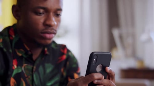 Close Up of African-American Teenager Sitting on Sofa Using Smartphone. Social Networks