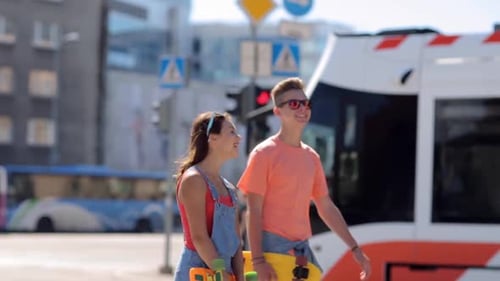 Pareja adolescente sonriente en patineta disfrutando de las vacaciones de verano en la ciudad