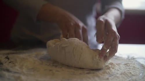 Frauenhände backen Pizzateig auf einem Marmortisch voller Mehl. Zeitlupe