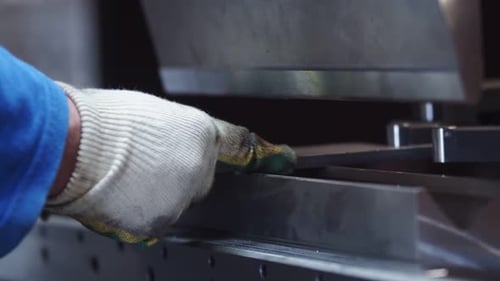 Closeup of a Master Worker in Protective Gloves Bending a Metal Workpiece on Hydraulic Sheet Bender