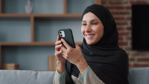 Woman with Head Covering Using Smartphone Indoors