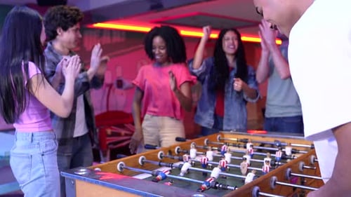 Friends Playing Foosball and Having Fun in Arcade