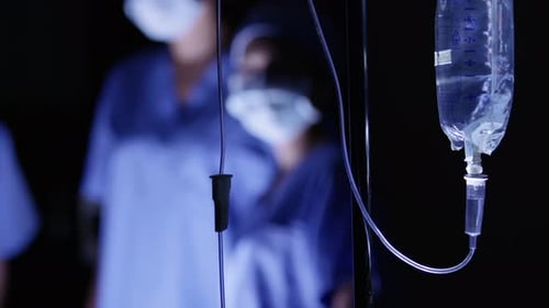 Iv drip close up scene in a hospital operating room with medical professionals