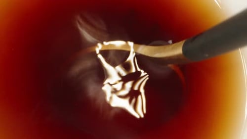 I stir sugar in tea with a spoon, top view. Dolly slider extreme close-up inside. Laowa Probe