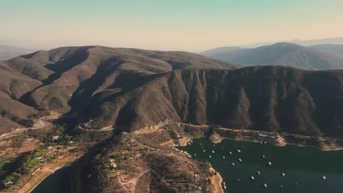 Aerial drone flying over a lake, water dam, with mountains at sunrise. Beautifull dreamy landscape.